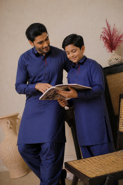 Father and child in matching blue outfits reading a book together.