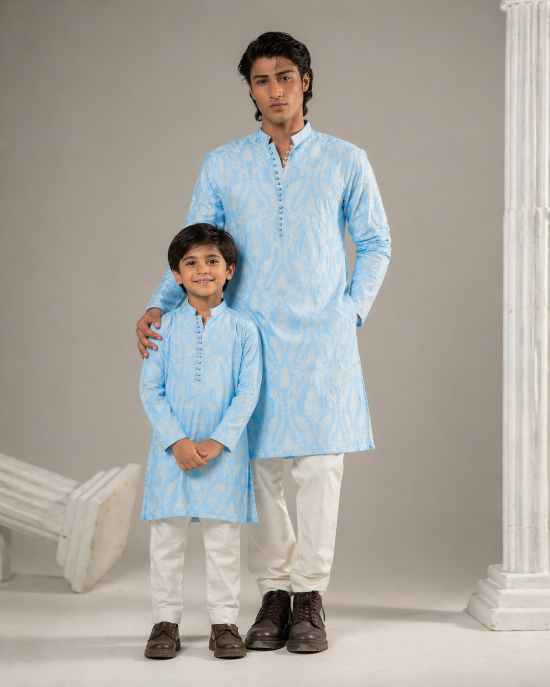 Two individuals wearing matching light blue kurta sets standing against a neutral background.