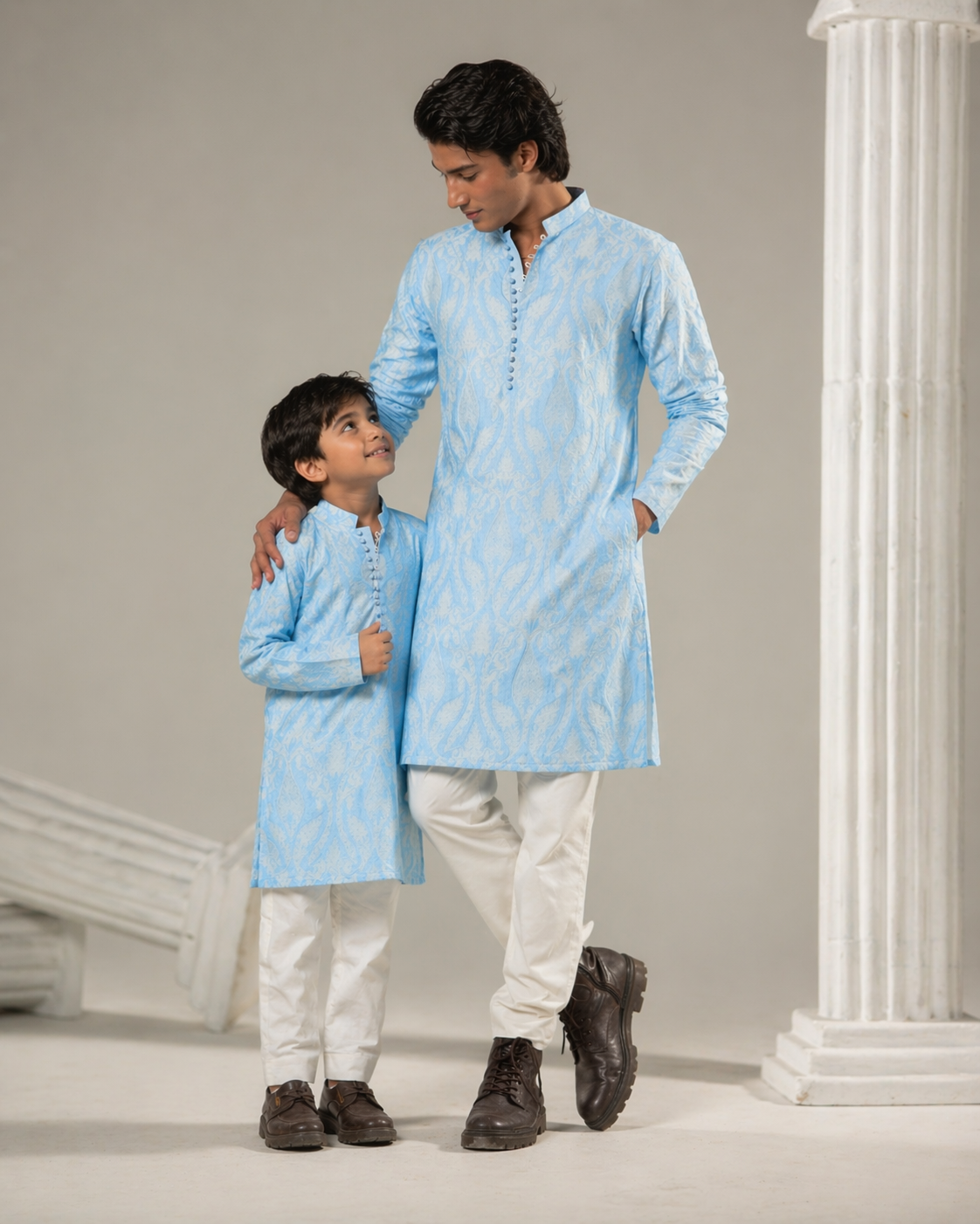 Two individuals wearing matching light blue kurta sets against a neutral background.