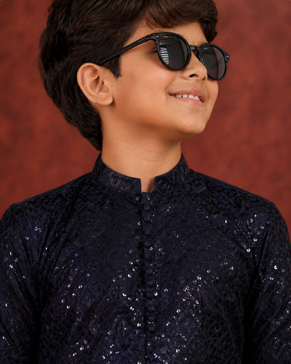 Young boy wearing a dark blue embroidered kurta with sunglasses