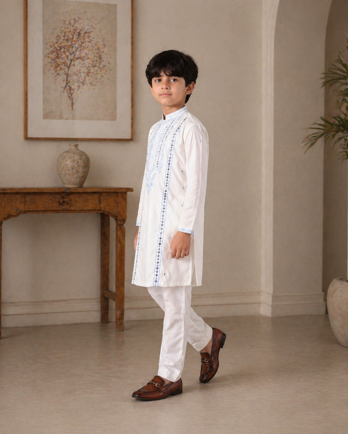 boy in a white traditional outfit standing in a room