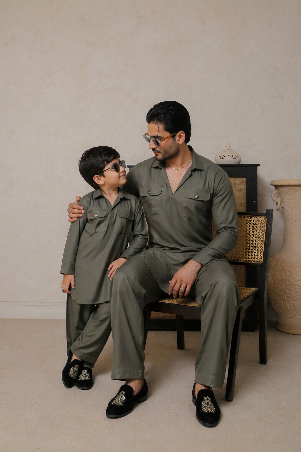 Man and child in matching green outfits sitting on a chair against a neutral background