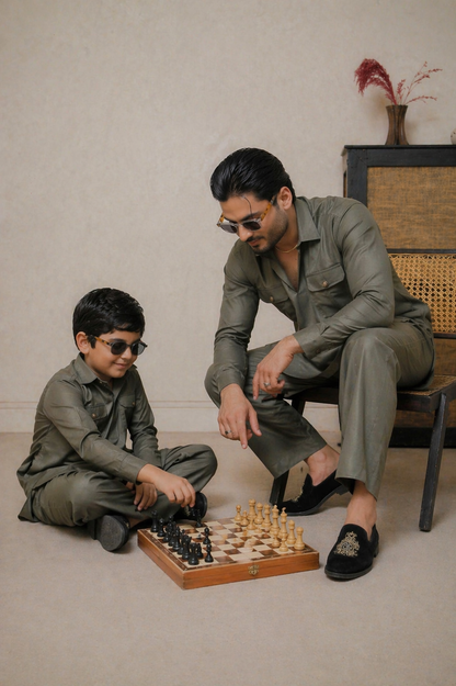 Man and child playing chess together in a room with a neutral background