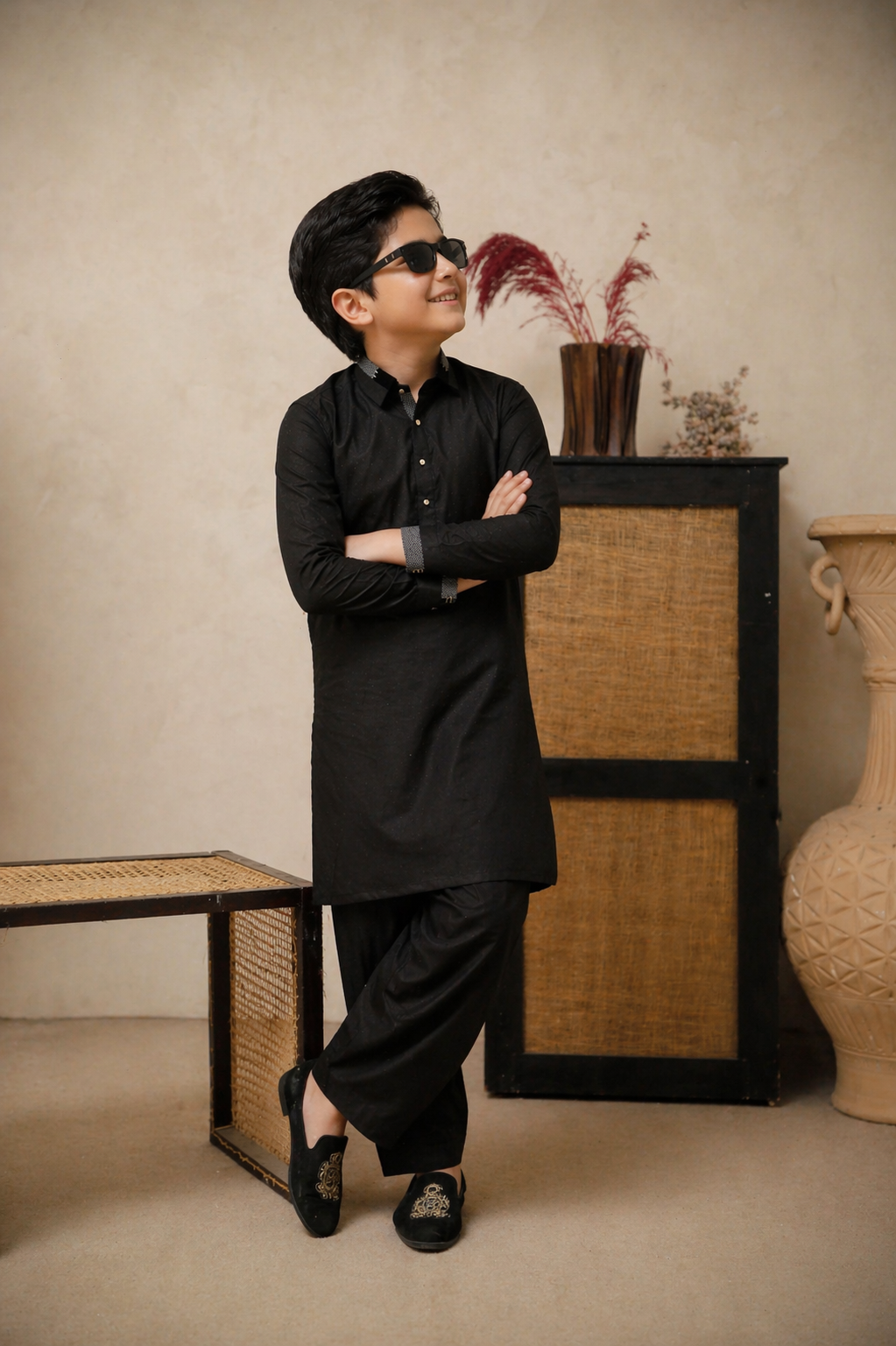 Person wearing a black outfit standing in a room with decorative elements.
